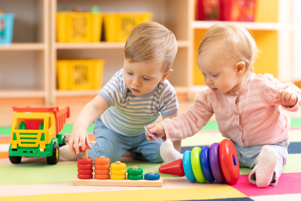 Two toddlers playing with stacking toys and a wooden truck at Young Explorers Club creche, Blanchardstown, Dublin 15