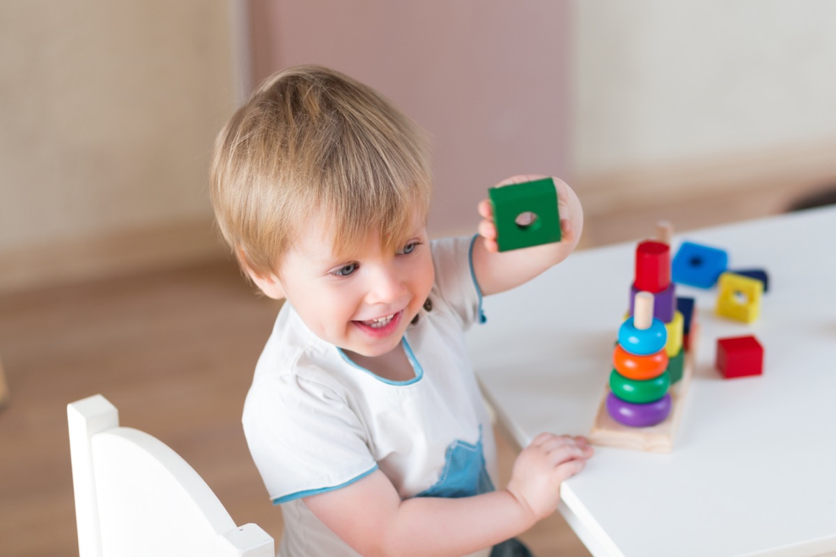 Toddlers room at Young Explorers Club, Dublin 15: a two-year-old stacking coloured blocks at a table